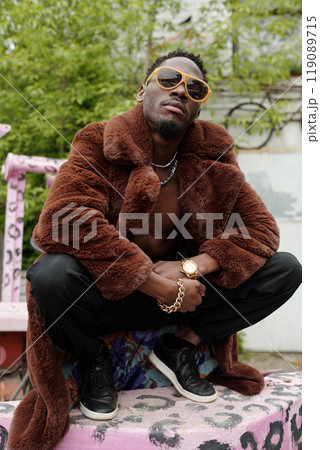 Stylish Young Man Wearing Fur Coat and Sunglasses Posing Outside Stylish Young Man Wearing Fur Coat and Sunglasses Posing Outside 119089715