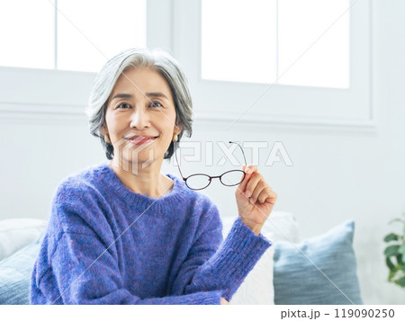 リビングルームでメガネを外すシニア女性 リビングルームでメガネを外すシニア女性 119090250