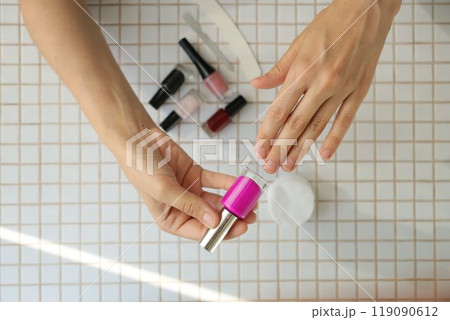 lady chooses color of nail polish. woman's hand and nail polish on table background. 119090612