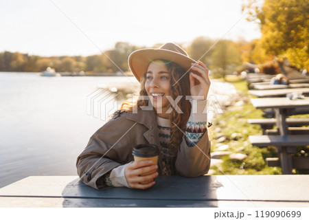 Fall concept woman drinking coffee on bench against backdrop of lake. Enjoying, solitude with nature Fall concept woman drinking coffee on bench against backdrop of lake. Enjoying, solitude with nature 119090699