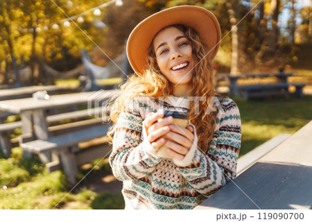Fall concept woman drinking coffee on bench against backdrop of lake. Enjoying, solitude with nature Fall concept woman drinking coffee on bench against backdrop of lake. Enjoying, solitude with nature 119090700