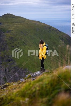 A Solo Female Hiker in a Bright Yellow Jacket Walking Along a Scenic Mountain Pathway 119092424
