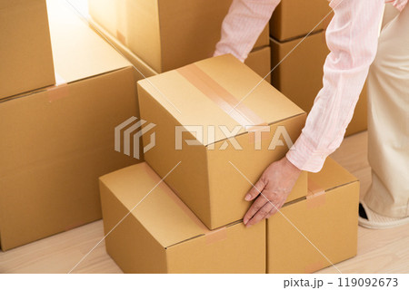引っ越しの荷物が入ったたくさんのダンボールを部屋に運ぶミドル女性 119092673