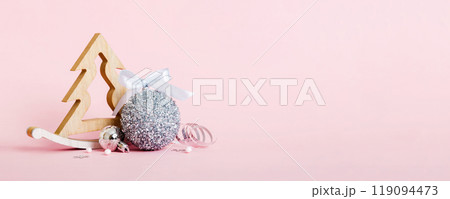 Christmas ball with decorative wooden tree on colored background. decoration bauble with ribbon bow with copy space 119094473