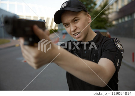 Woman patrol police officer aiming with handgun at city street 119094814