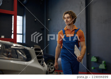 Smiling repairman car technician walking with clipboard in hands 119094899