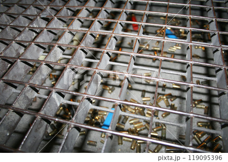 View of spent bullet casings through a metal grate 119095396