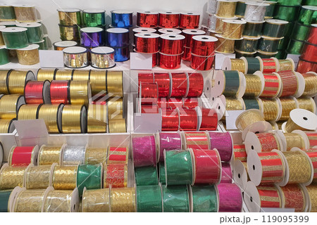 Various colorful ribbons neatly arranged on shelves 119095399