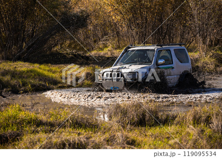 Small japanese suv crossing water obstacle in a bog terrain 119095534