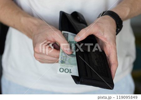 Man holding a black wallet with 100 Polish zloty. Closeup. 119095849