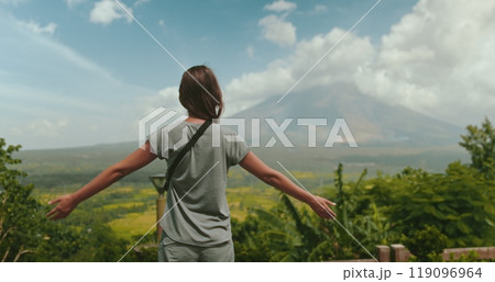 Young woman is embracing the breathtaking beauty of a tropical landscape, with the majestic mayon volcano standing tall in the distance 119096964