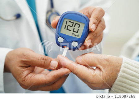 Asian doctor using digital glucose meter for check sample blood sugar level to treatment diabetes. 119097269