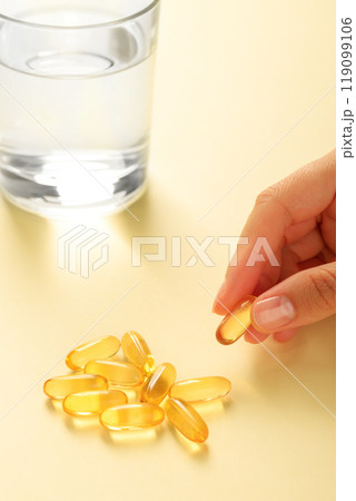 Hand picks up one omega-3 capsule from a handful of similar capsules. Hand picks up one omega-3 capsule from a handful of similar capsules. 119099106