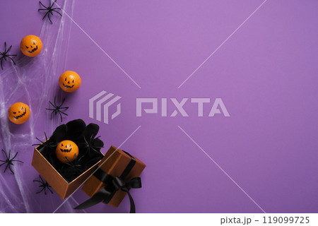 Halloween Mini pumpkins and spiders with spider webs in gift box on purple background. Background for Halloween cards, banners, invitations. Place for your text. Halloween Mini pumpkins and spiders with spider webs in gift box on purple background. Background for Halloween cards, banners, invitations. Place for your text. 119099725