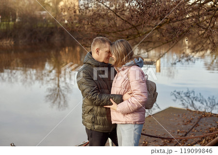 Loving couple on the shore of the pond in the park in autumn. A man and a woman. A couple, lovers on the shore of the lake on a walk. Autumn Romance by the Lake: Happy Couple's Lakeside Leisure Loving couple on the shore of the pond in the park in autumn. A man and a woman. A couple, lovers on the shore of the lake on a walk. Autumn Romance by the Lake: Happy Couple's Lakeside Leisure 119099846