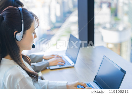 オフィスでヘッドセットをつけて対応する若い女性オペレーター 119100211