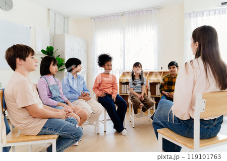 Group study session with diverse students seated in a circle engaging in a classroom discussion led by a teacher, emphasizing interactive learning and participation in a primary education environment Group study session with diverse students seated in a circle engaging in a classroom discussion led by a teacher, emphasizing interactive learning and participation in a primary education environment 119101763