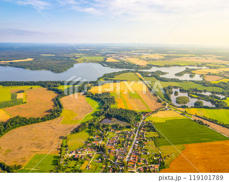 This stunning aerial view showcases Rozmberk Pond near Trebon, Czechia, revealing its expansive waters surrounded by lush green fields and patches of farmland under a clear sky. 119101789