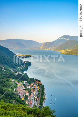 The tranquil waters of Lake Como reflect the lush greenery and charming towns along its banks, showcasing a serene landscape surrounded by majestic mountains at dusk. The tranquil waters of Lake Como reflect the lush greenery and charming towns along its banks, showcasing a serene landscape surrounded by majestic mountains at dusk. 119102602