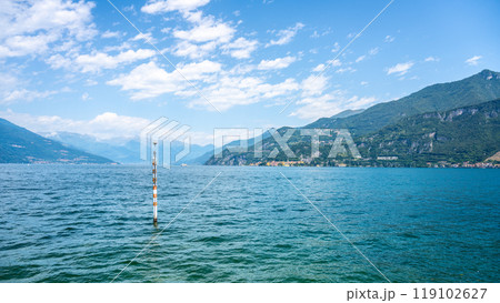 Gentle ripples form on Lake Como's surface as a serene atmosphere envelops the landscape. The mountains stand tall in the background, showcasing the beauty of this Italian gem. 119102627