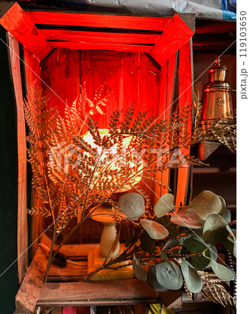 Warm, glowing lamp is surrounded by delicate dried flowers, creating a cozy and inviting atmosphere. Soft light casts rich, amber tones, enhancing the rustic charm of the wooden setting Warm, glowing lamp is surrounded by delicate dried flowers, creating a cozy and inviting atmosphere. Soft light casts rich, amber tones, enhancing the rustic charm of the wooden setting 119103650