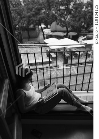 A Contemplative Moment A Young Woman Engaged in Reading While Sitting by the Window Nearby 119104125