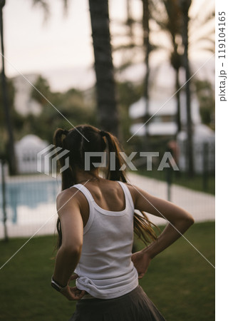 A young woman is truly enjoying her moments of relaxation by the serene poolside area A young woman is truly enjoying her moments of relaxation by the serene poolside area 119104165
