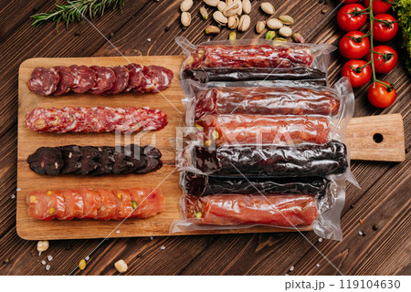 Assorted gourmet salami slices with nuts and spices on board, charcuterie and deli platters 119104630