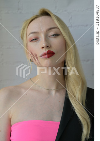 Close-up portrait of a blonde girl look at camera with different make-up on half of her face on white background 119104837