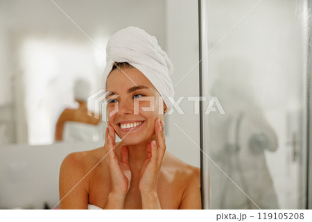 A Radiant Woman Enjoys Her Skincare Routine After a Refreshing Shower While Wrapped in a Towel A Radiant Woman Enjoys Her Skincare Routine After a Refreshing Shower While Wrapped in a Towel 119105208