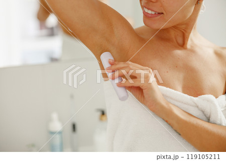 A woman is performing underarm waxing in her bathroom for beauty and personal care purposes 119105211