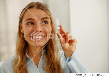 A Happy Woman is Holding a Skincare Product That Promotes Radiant and Glowing Skin 119105226