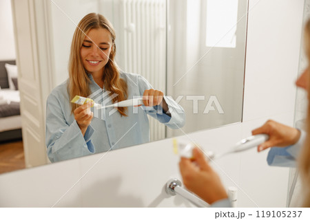A Smiling Woman Gleefully Brushing Her Teeth in a Beautiful, Modern Bathroom Space 119105237