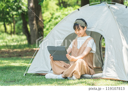 キャンプ場・レジャー施設でテントでタブレットを使う女の子 キャンプ場・レジャー施設でテントでタブレットを使う女の子 119107813