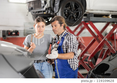 Male car repair shop worker consulting female client 119109628