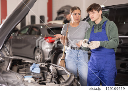 Woman car owner explains car engine problem to a car service mechanic 119109639