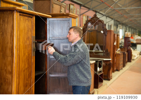 Man looking for wooden furniture in store 119109930