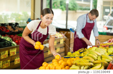 Girl seller was distracted for minute and stands smiling with ripe oranges in hands Girl seller was distracted for minute and stands smiling with ripe oranges in hands 119110049
