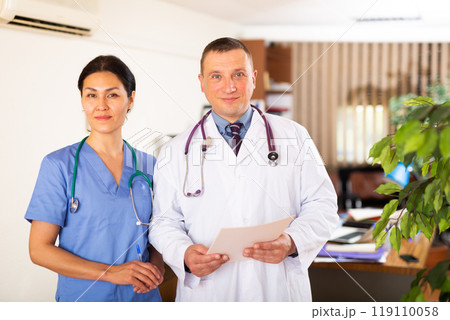 Two confident professional fellow doctors standing in office 119110058