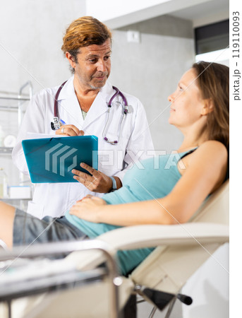Positive doctor conducting questionnaire of female patient in medical office Positive doctor conducting questionnaire of female patient in medical office 119110093