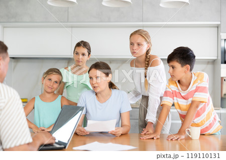Man with laptop does remote work, frustrated wife reads letter, and alarmed children stand nearby Man with laptop does remote work, frustrated wife reads letter, and alarmed children stand nearby 119110131