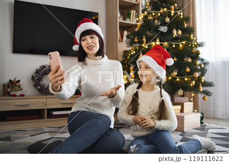 Mother and daughter video call by Christmas tree 119111622