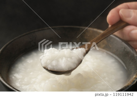 お粥　おかゆをスプーンで持ち上げる 119111942
