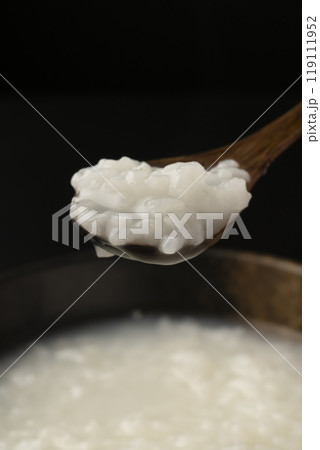 お粥　おかゆをスプーンで持ち上げる 119111952