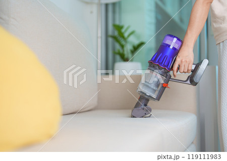Woman cleaning Sofa with cordless Vacuum cleaner. Housewife using wireless Vacuum for big cleaning home. Housework, Housecleaning, Housekeeping, Removes dust, Domestic hygiene and daily routine Woman cleaning Sofa with cordless Vacuum cleaner. Housewife using wireless Vacuum for big cleaning home. Housework, Housecleaning, Housekeeping, Removes dust, Domestic hygiene and daily routine 119111983