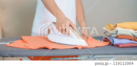 Woman hold Electric hot iron press T shirt clothes on ironing board, Intelligent automatic steam iron. Laundry, Housework, Housekeeping, Domestic hygiene, household of chores and daily routine concept Woman hold Electric hot iron press T shirt clothes on ironing board, Intelligent automatic steam iron. Laundry, Housework, Housekeeping, Domestic hygiene, household of chores and daily routine concept 119112004