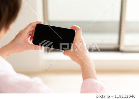 マンションの内覧でスマホを見るミドル女性 119112046