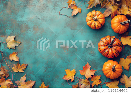 Pumpkins and vibrant autumn leaves arranged on a textured turquoise background, evoking a festive fall and Thanksgiving vibe. 119114462