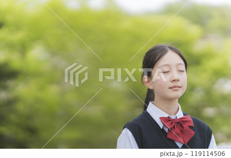 鮮やかなグリーンの木の前で目を閉じる少女 鮮やかなグリーンの木の前で目を閉じる少女 119114506