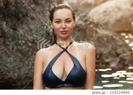 Beautiful girl in a black swimsuit in a blue lagoon among the rocks Beautiful girl in a black swimsuit in a blue lagoon among the rocks 119114895